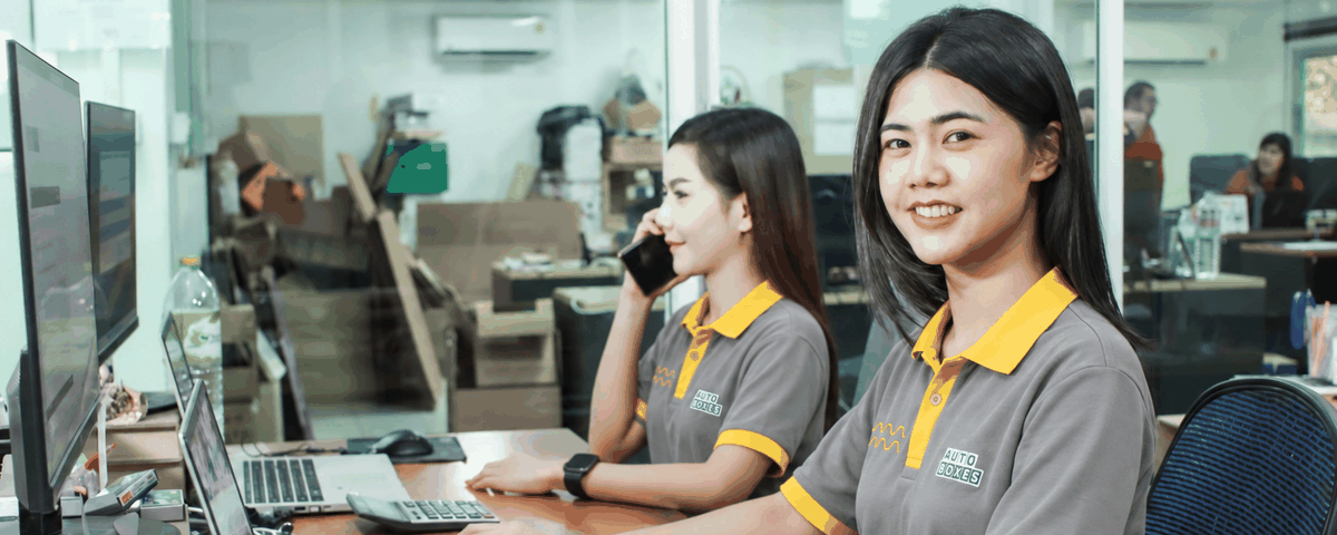 Auto Boxes customer service staff at their desks, one on the phone and one working at a laptop